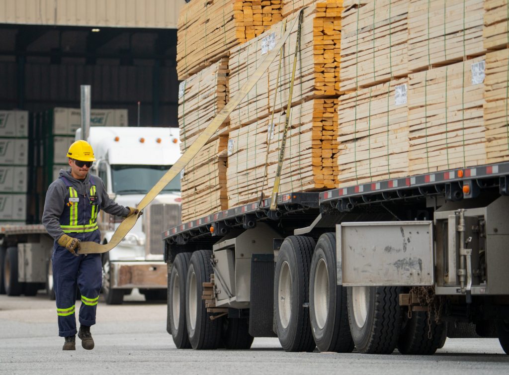 worker standing next to load of lumber